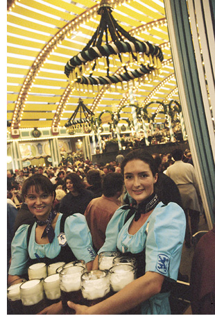 barmaids carry heavy steins of Bavarian lager