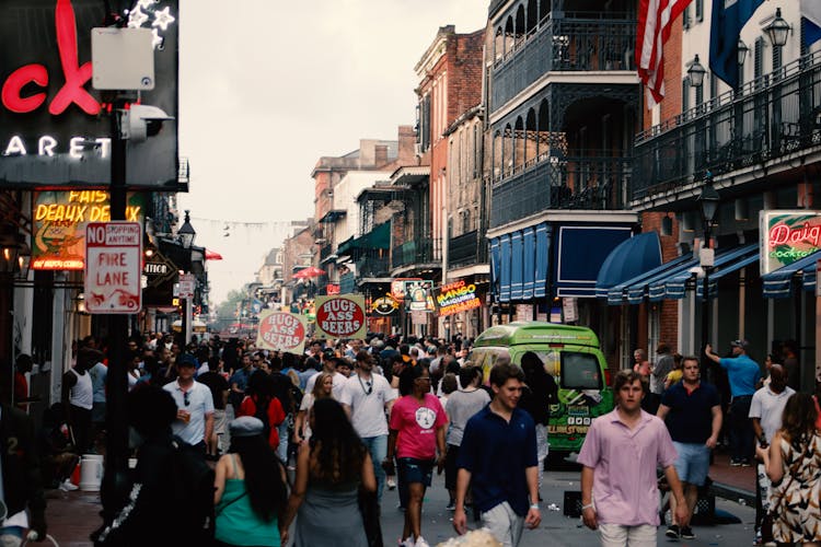 A crowded street in New Orleans, shops and restaurants with neon signs.